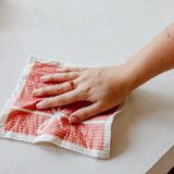 close up of wiping a table with a pink swedish dishcloth