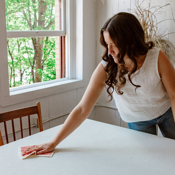 woman wiping a table with a reusable paper towel