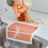pink swedish dishcloth sitting on the edge of a sink