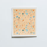Terrazzo swedish dishcloth with a peach background featuring pops of blues, orange and purple colours