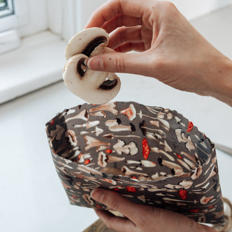 cut mushrooms being dropped into a snack pouch made out of the large mushroom beeswax wrap